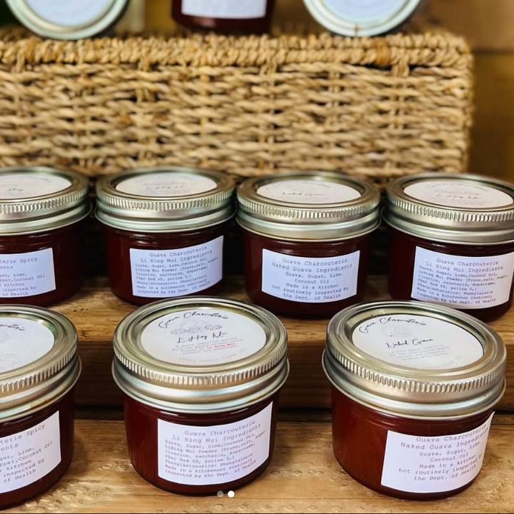 Jars of guava charcuterie paste stacked on a wooden board in front of a woven basket