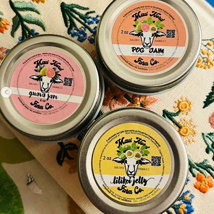 Three jars, guava jam, POG jam and lilikoi jelly, on embroidered floral fabric